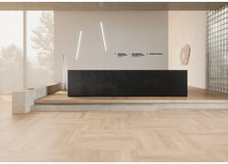 Helle Empfangshalle mit Holzboden im Würfelmuster.