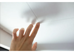 Hand drückt weiße Deckenplatte ein