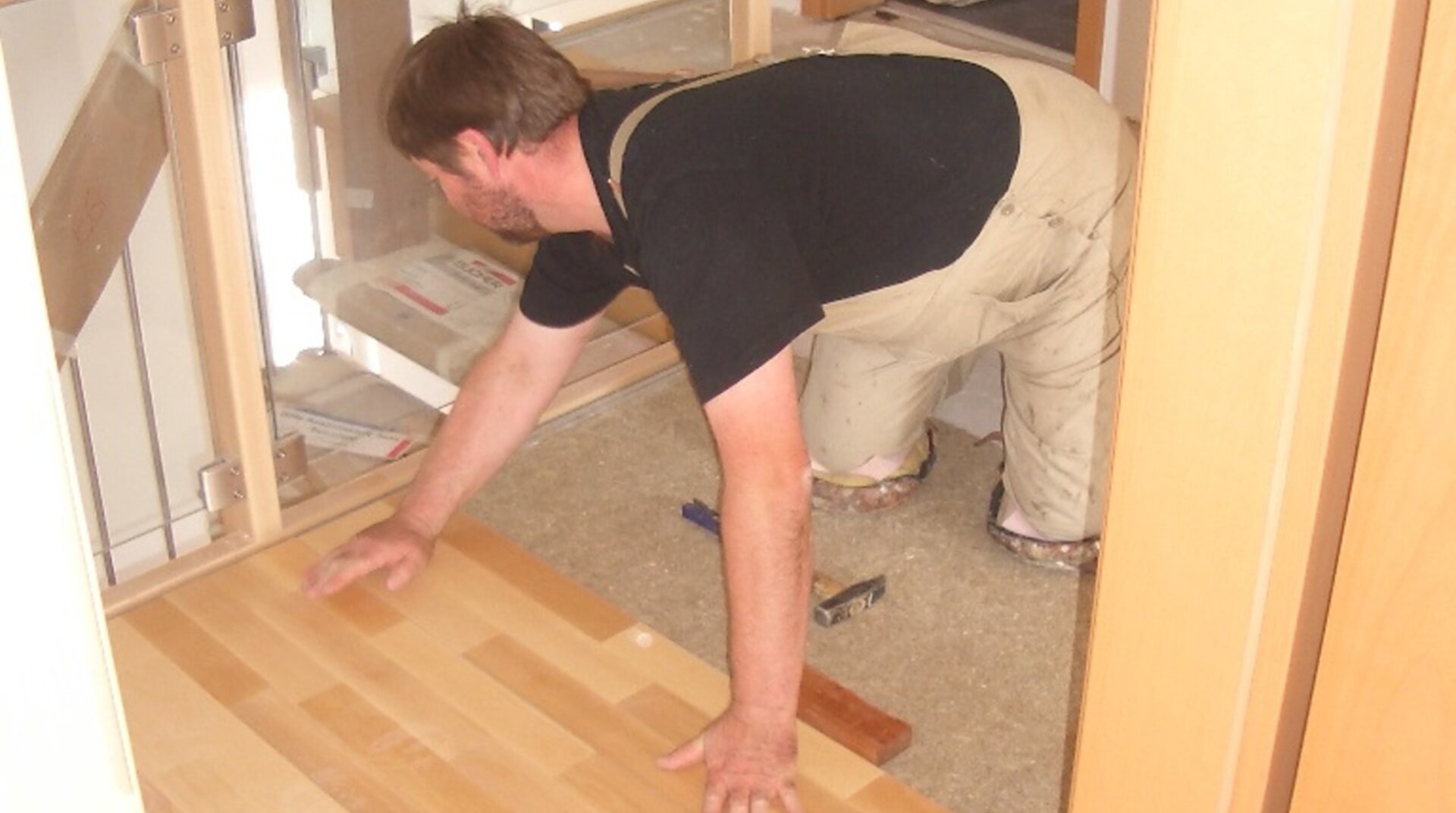 KHB-Creativ EFH Talheim, Mann beim Verlegen von Parkett im Flur