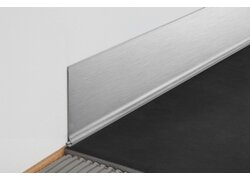Detailausschnitt einer architektonischen Ecke, an der eine schwarze Fläche auf eine strukturierte Wandfläche trifft, getrennt durch ein Edelstahlwinkelprofil.